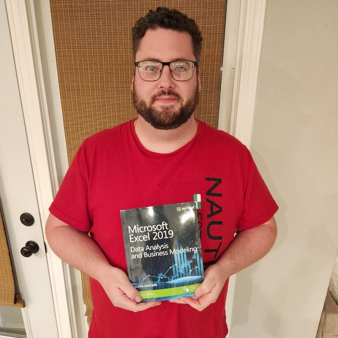 A picture of Anthony Justus holding a Microsoft Excel 2019 Data Analysis and Business Modeling textbook.